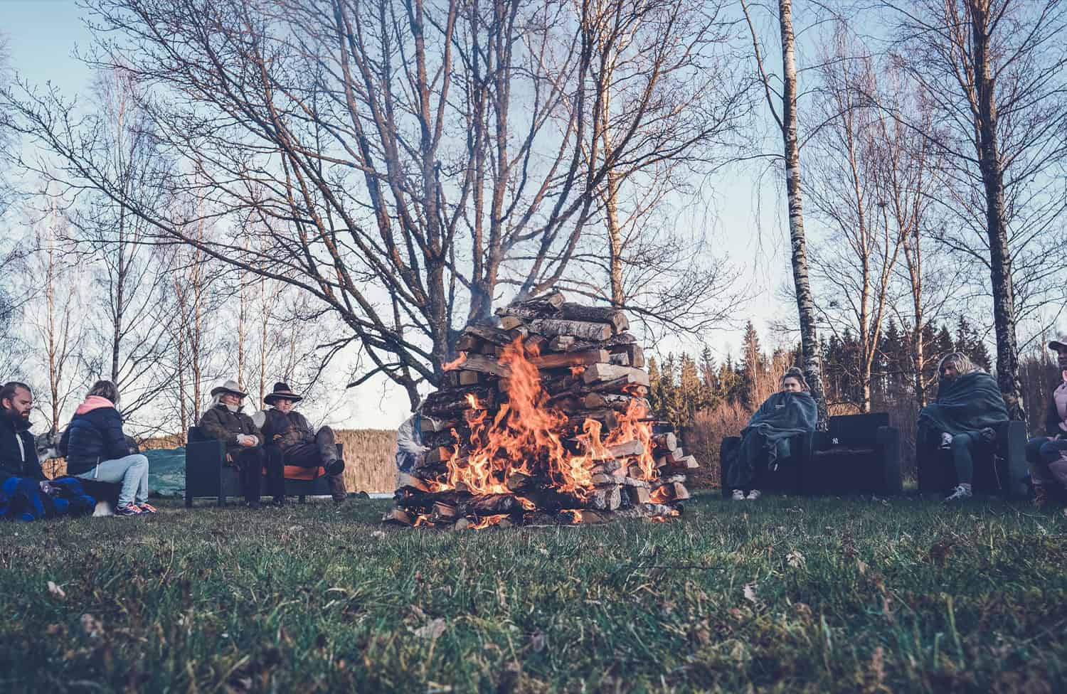 Ett sällskap samlat runt en stor eld utomhus