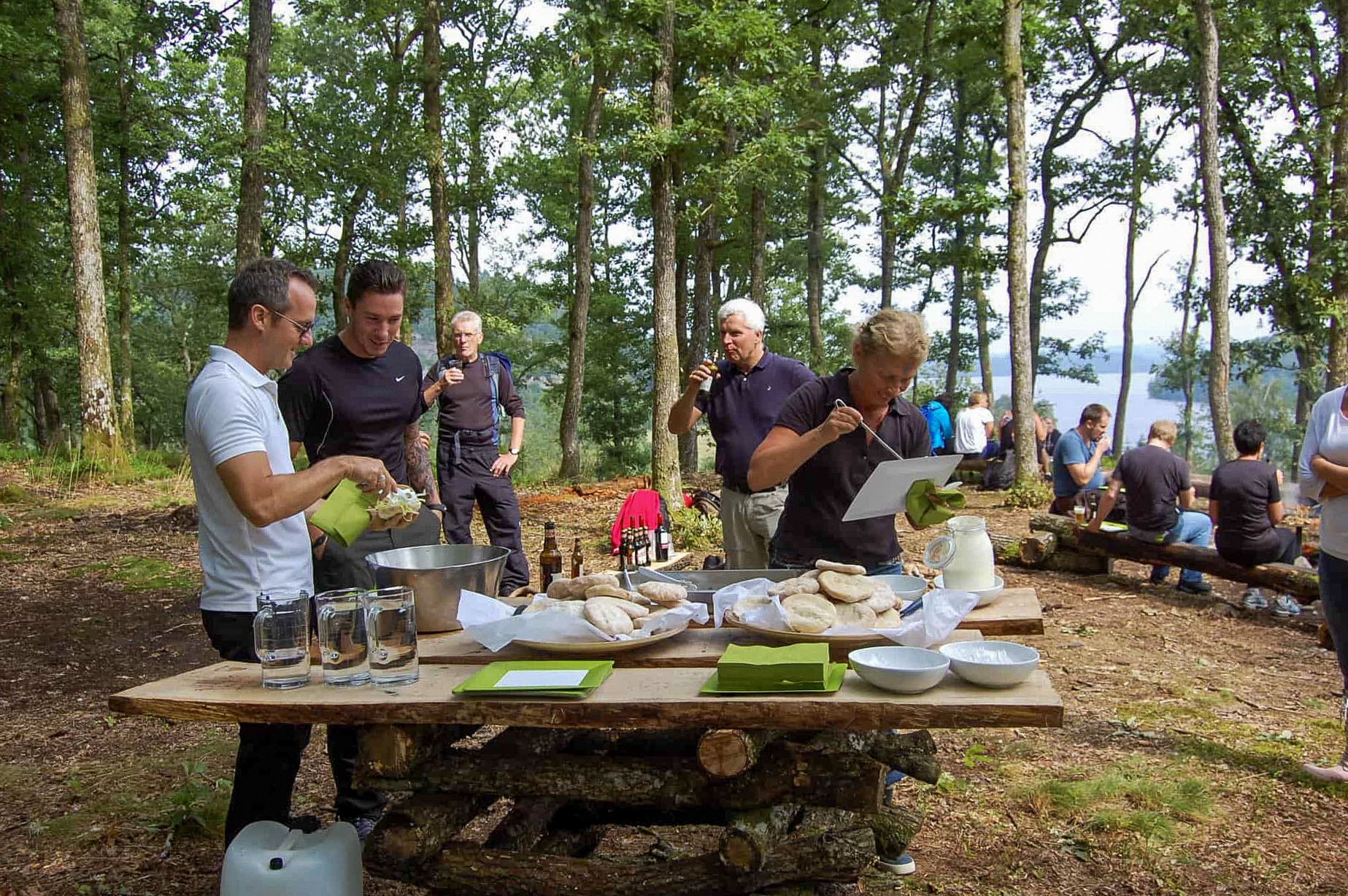 A group of companies eating and collaborating outdoors by the lake